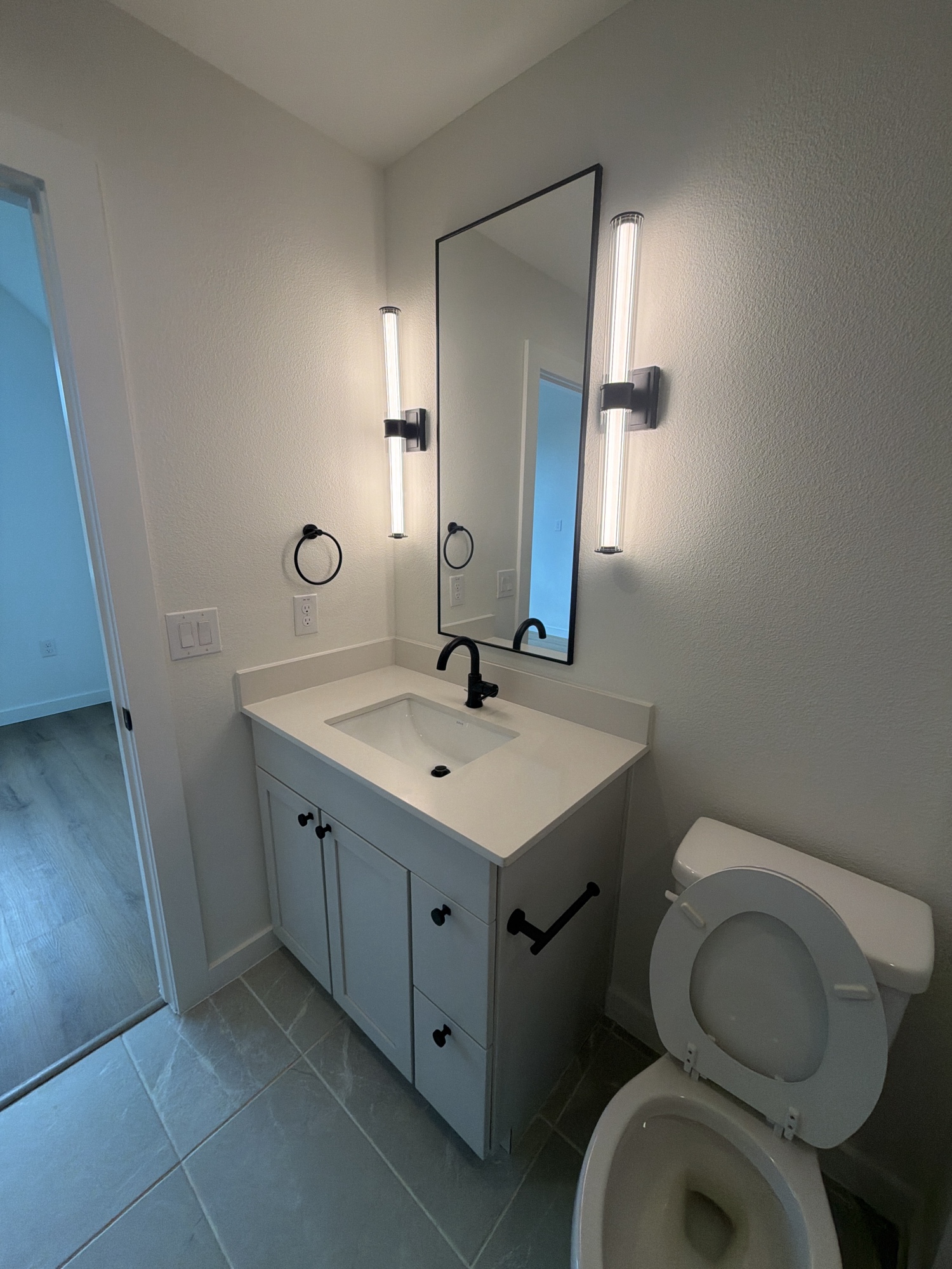Bathroom vanity with black sconce lights and mirror