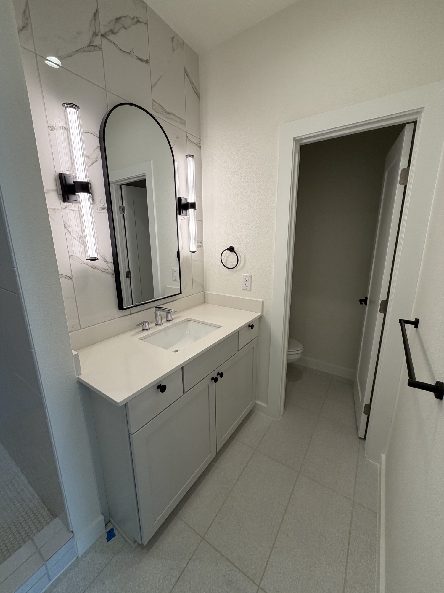Bathroom vanity with marble tile wall and sconce lighting
