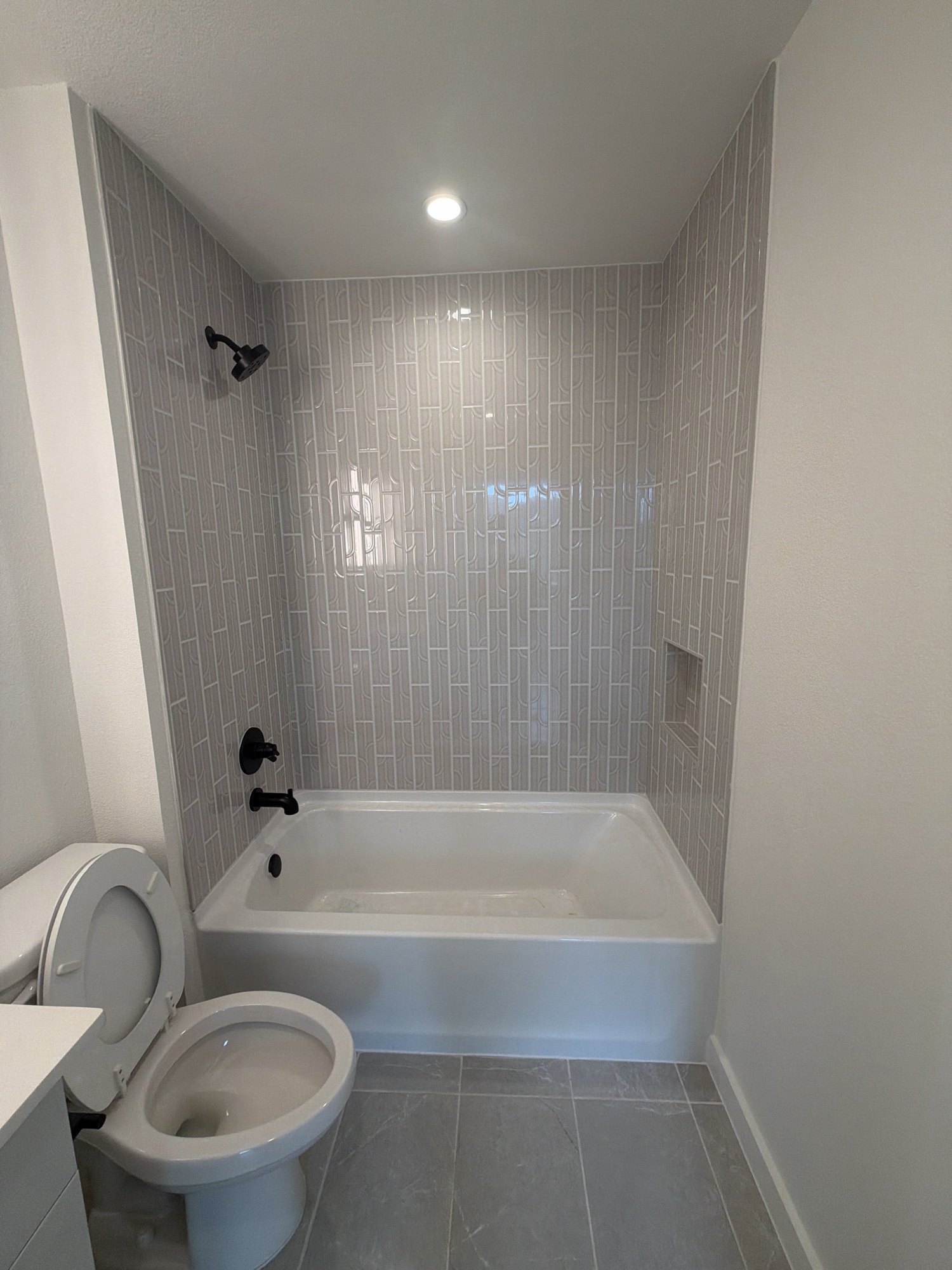 Tub and shower with gray tile and matte black fixtures