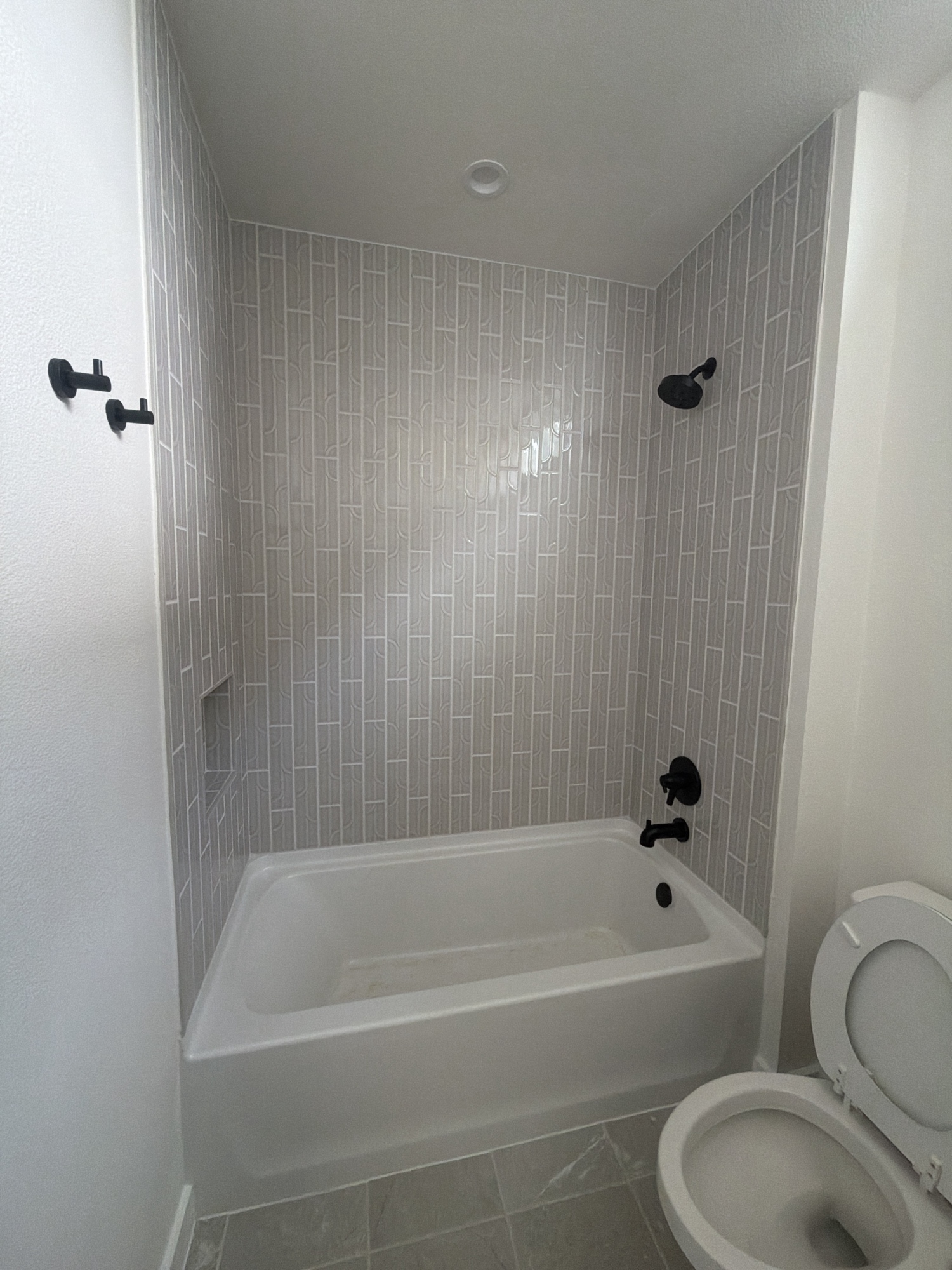 Tub and shower with vertical tile and matte black fixtures